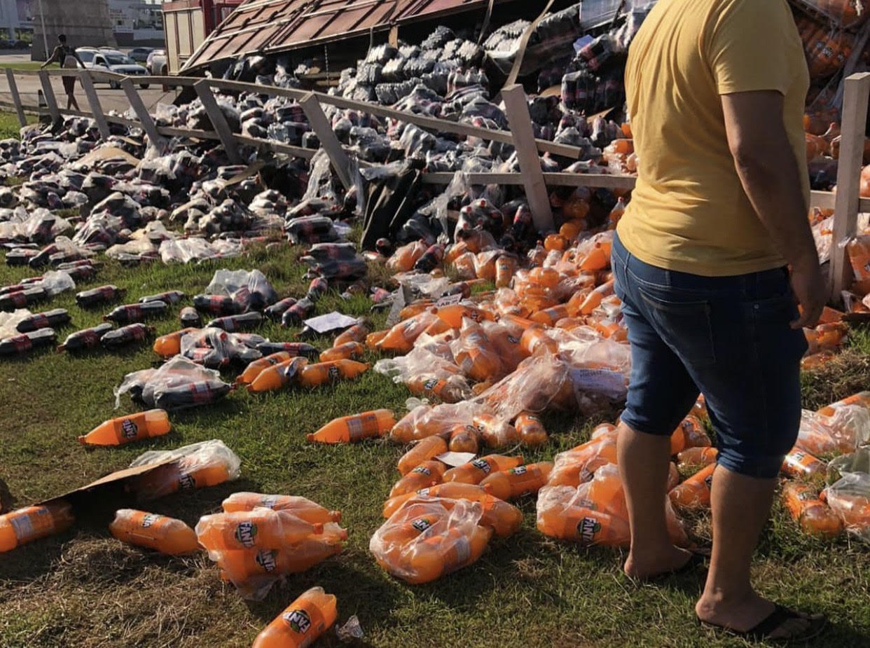 Após carreta tombar em rotatória, carga de Fanta e Coca-Cola fica espalhada na lateral da Via Verde