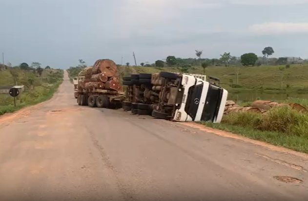BR-364 em péssimas condições: carreta carregada com toras de madeira tomba e motorista fica ferido
